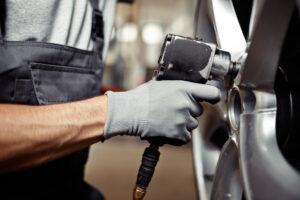 A young man is repairing a car at his work: car service and maintenance.